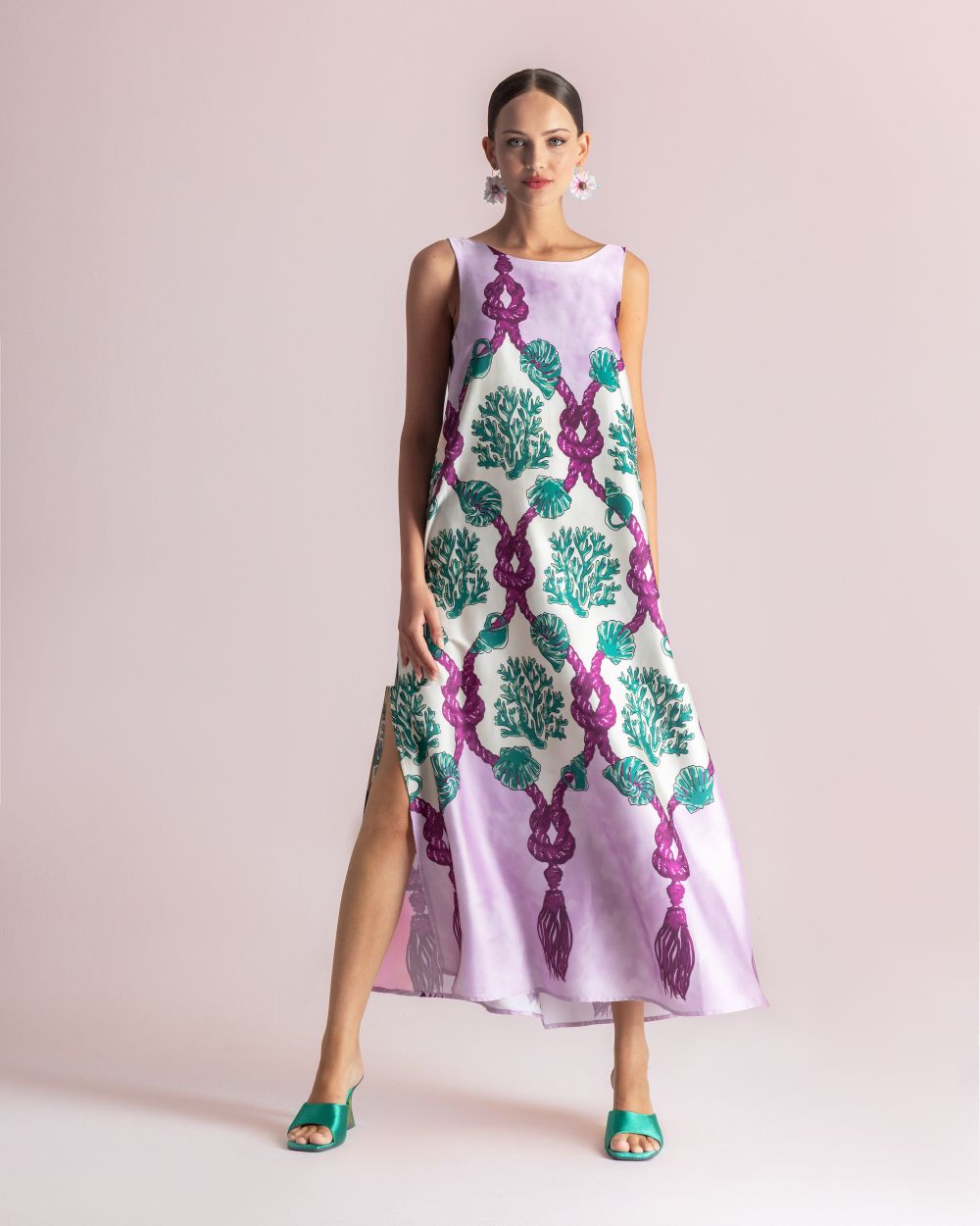 Model in a lavender sleeveless maxi dress featuring a bold purple rope motif and teal seaweed patterns, with a side slit; paired with teal sandals.