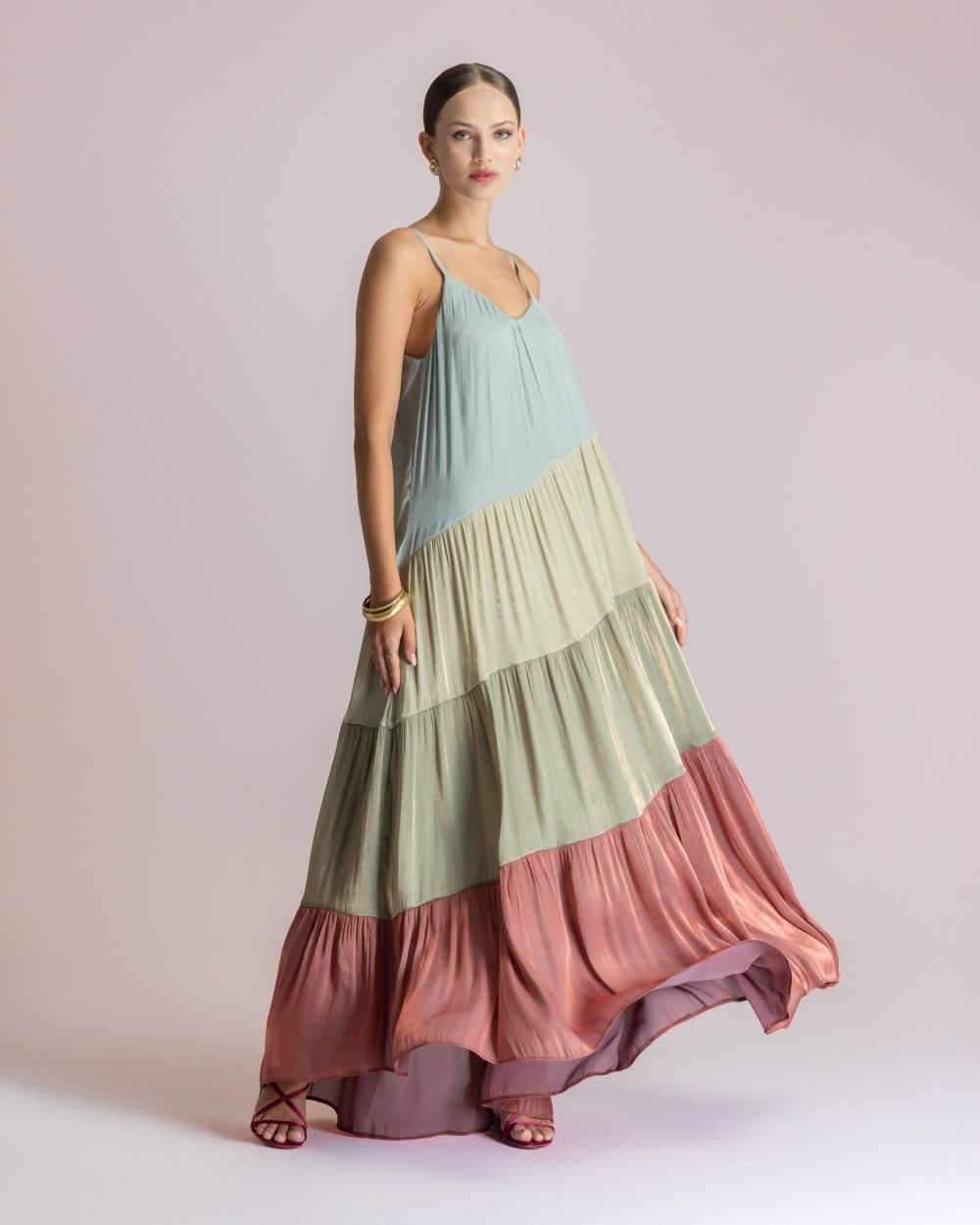 Sleeveless, pastel-tiered maxi dress in blue, cream, and pink; model poses in a studio backdrop.